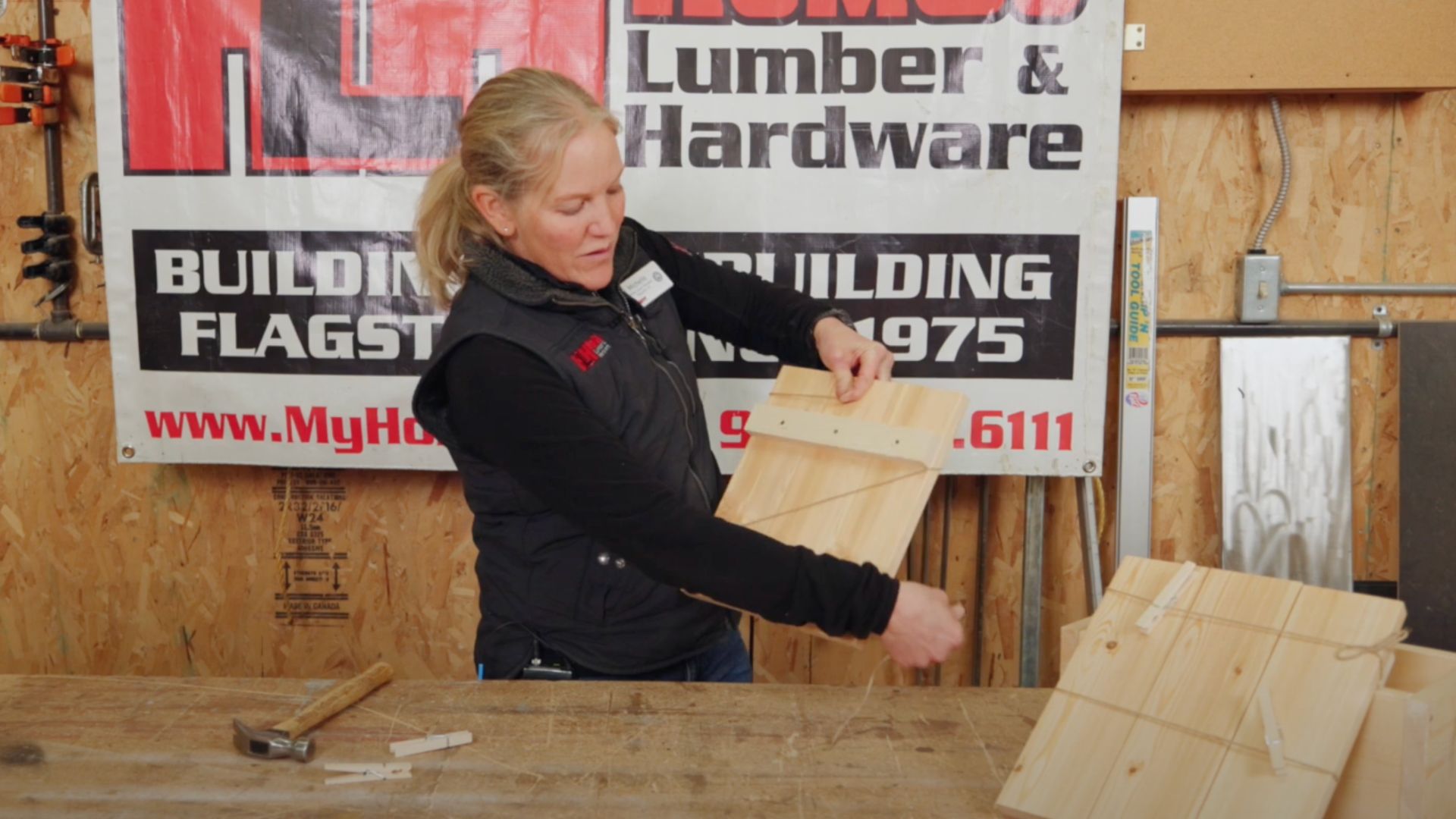 woman tying twine around nailed together wooden planks 